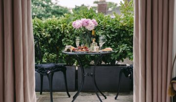 breakfast table with elegant flowers and wineglasses on veranda of classic styled villa